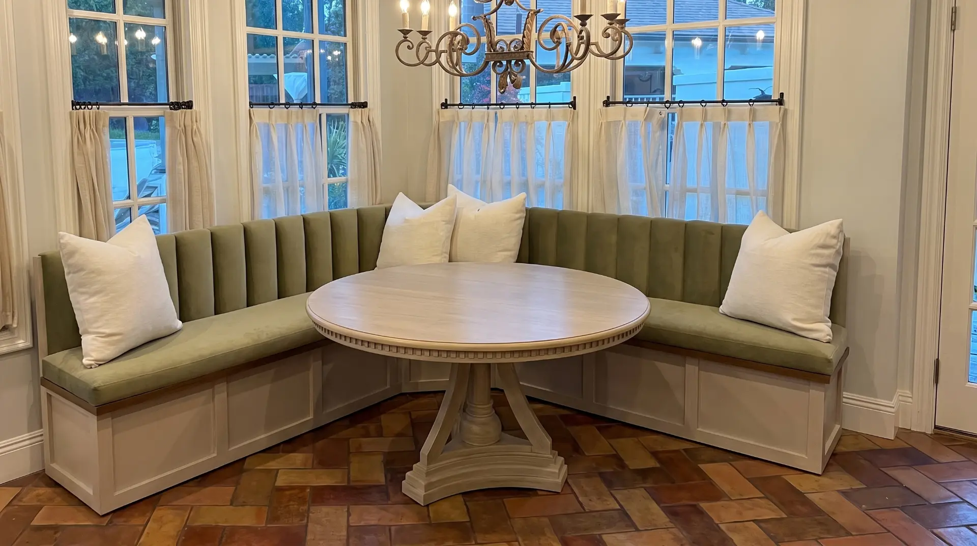 Green channel tufted corner banquette with a round wood table
